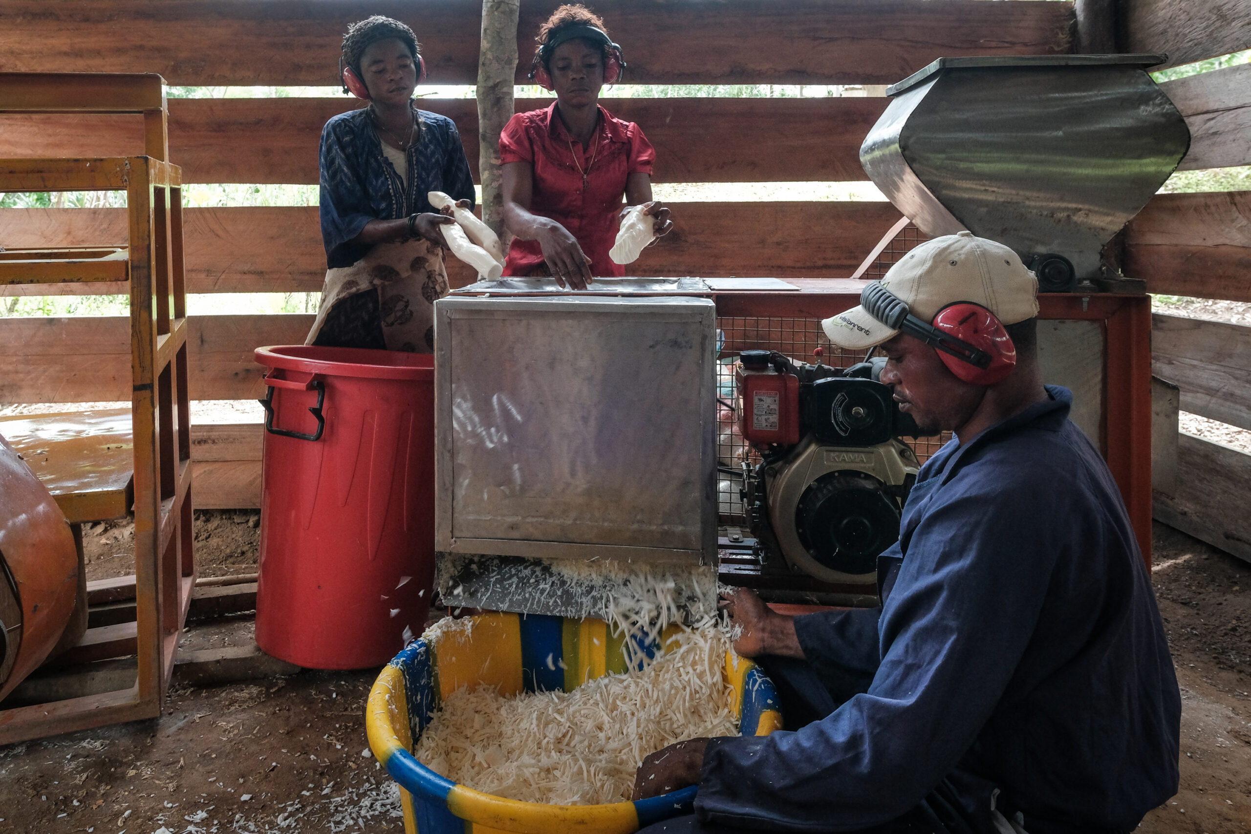 A photo of three people inside a barn using a machine to shred feed.