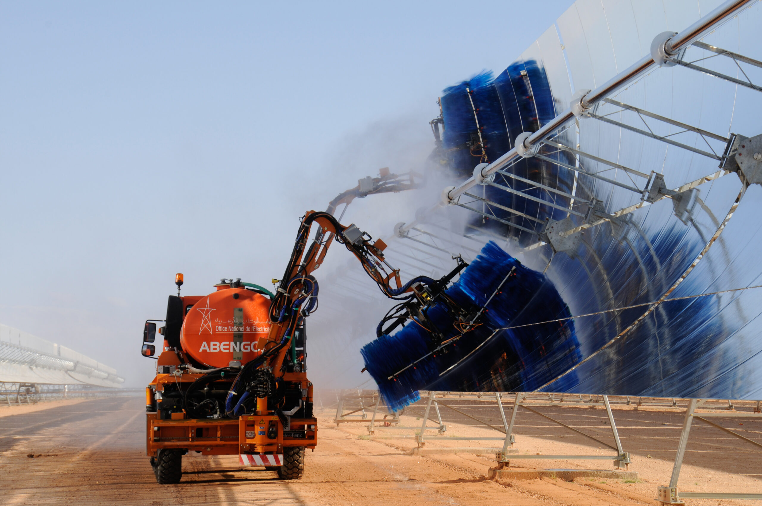 A photo of a truck washing solar panels in a deserted landscape.