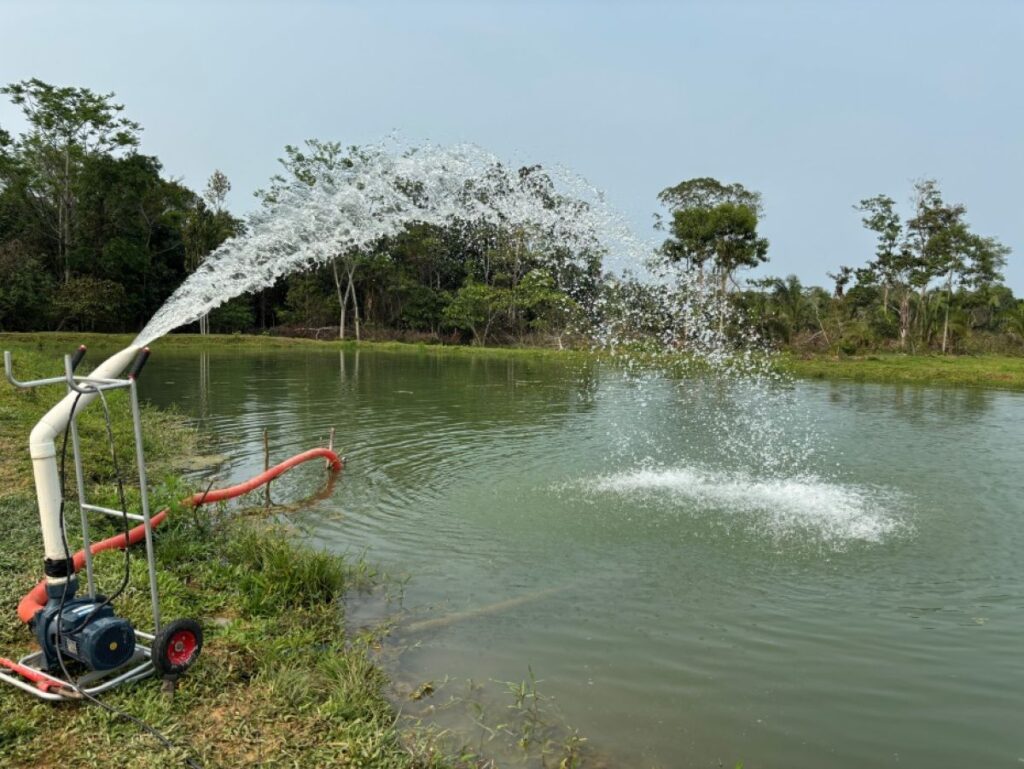 A photo of a lake in Bolivia. There is a large pipe dispensing water that is going into the lake.